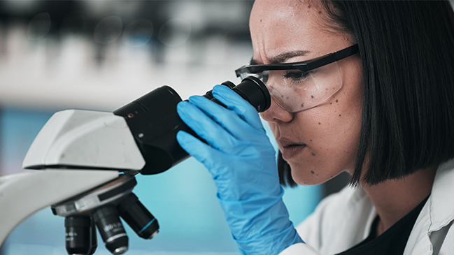 Laboratory personnel looking into a microscope